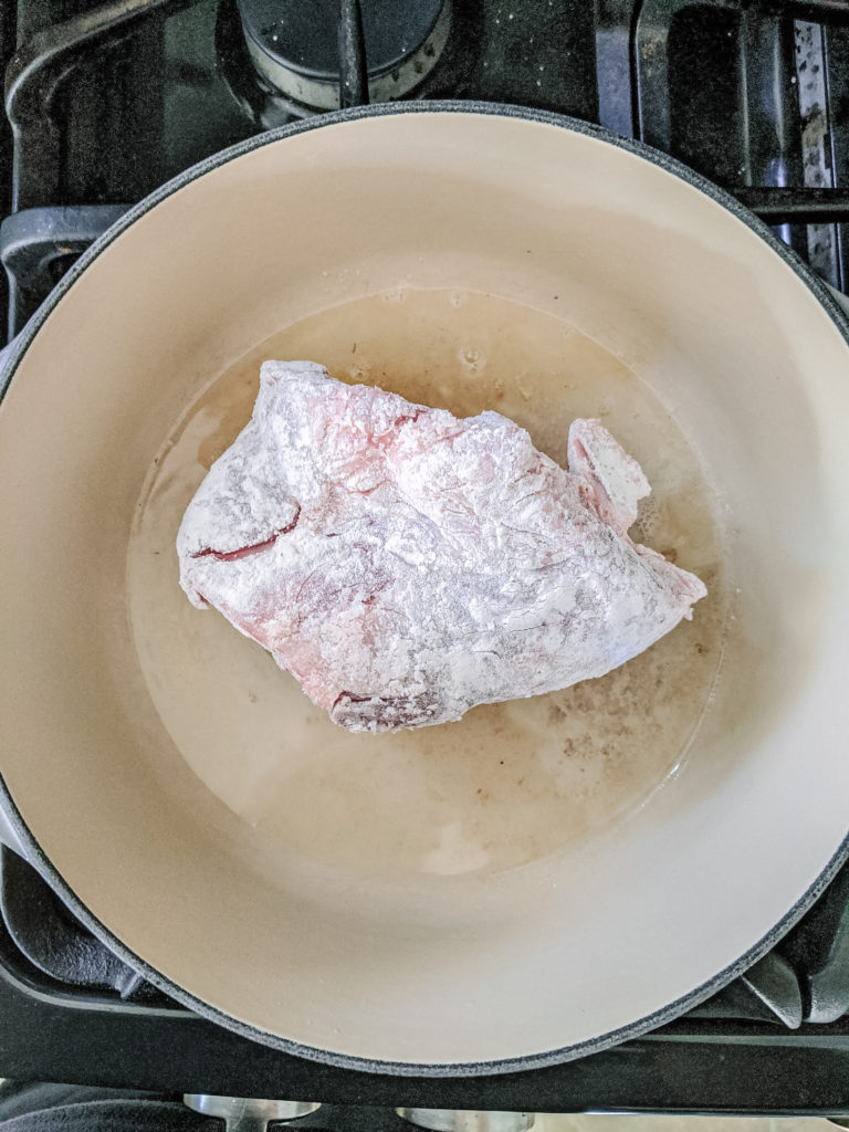 Raw pork shank cooking in le creuset pot 