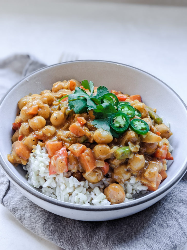 Vegan chickpea curry with rice in a small bowl on plain background 