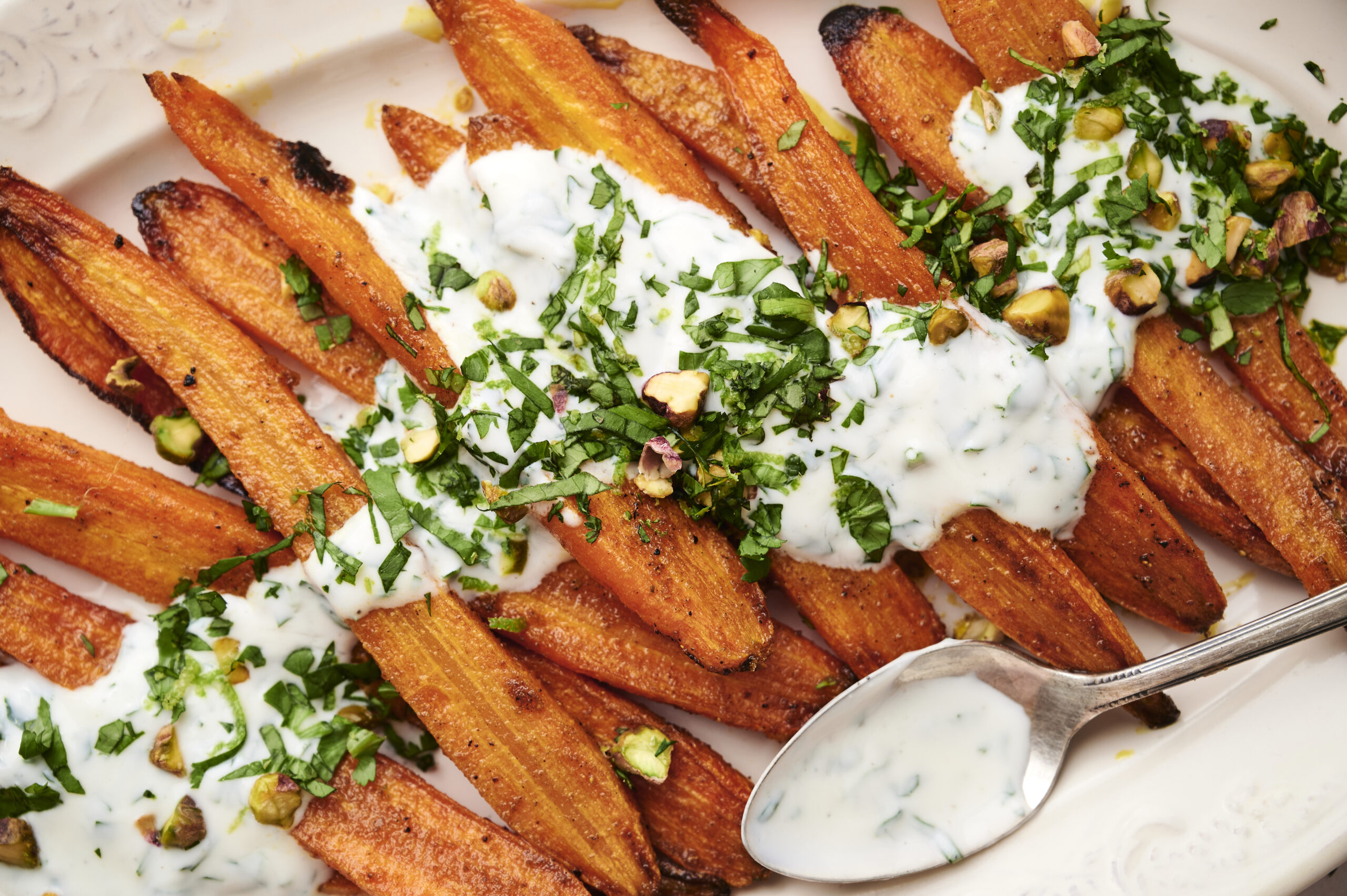 Roasted curry carrots with herb yogurt on a serving plate