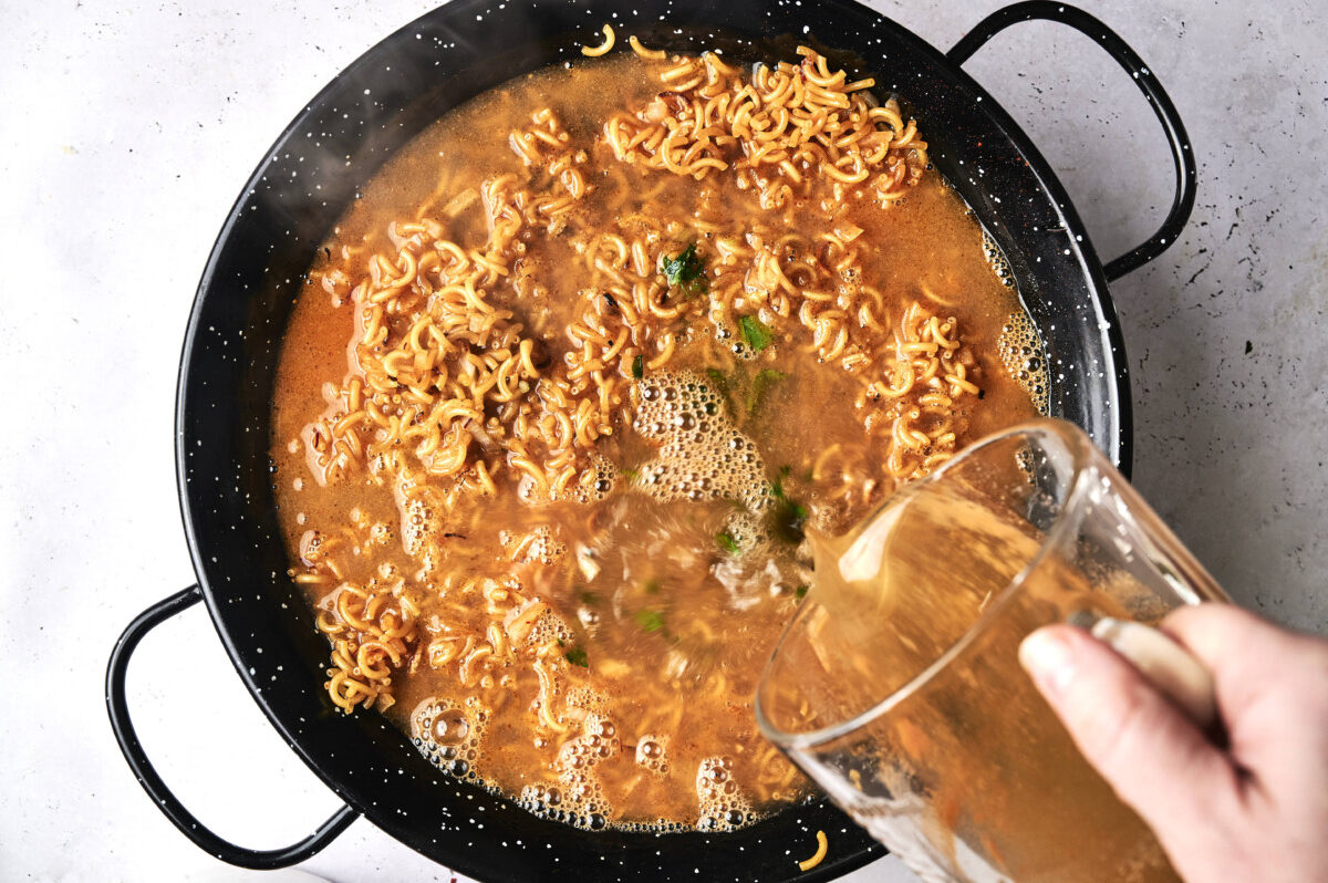 Adding broth to fideua 